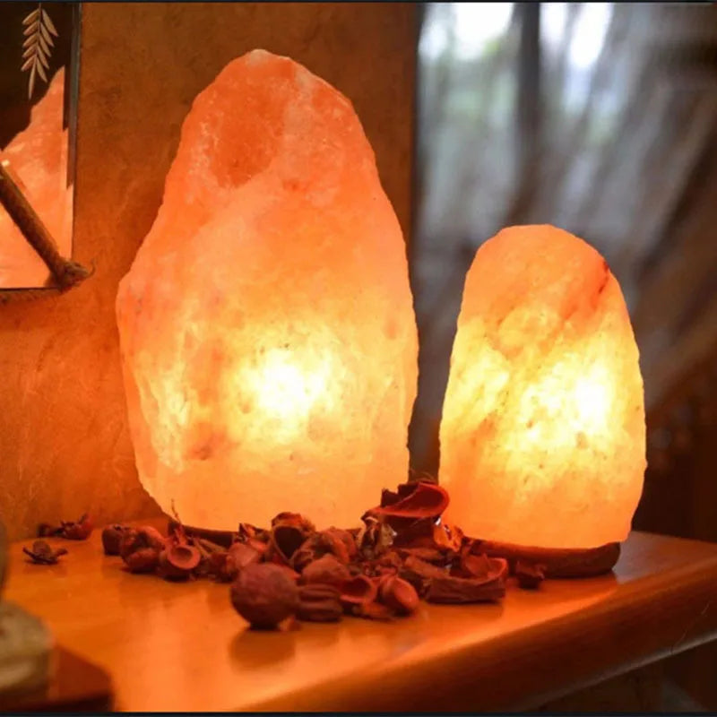 Two natural-cut Himalayan salt lamps glowing warm amber on a wooden shelf beside a mirror