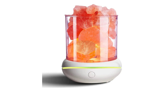 A compact USB salt lamp with pink rock salt chunks in a clear cylinder on a white base, lit pink