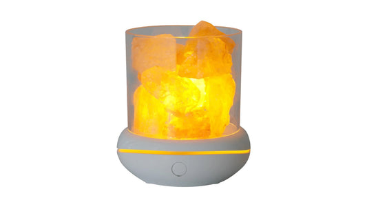 A compact USB salt lamp with loose salt chunks in a clear shade on a white base, lit amber