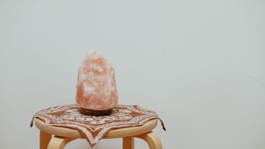 A natural-cut Himalayan salt lamp on a small wooden stool against a plain wall