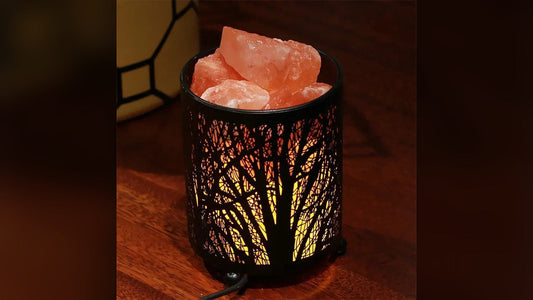 Forest-pattern metal basket lamp filled with lit pink Himalayan salt chunks on a wooden table