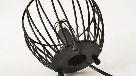 The underside of a wire-frame salt lamp showing its bulb socket, base plate and cord entry