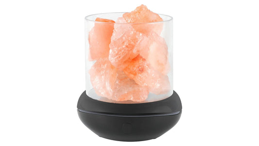 Unlit Himalayan salt lamp with rough pink salt chunks in a clear cylinder on a dark base